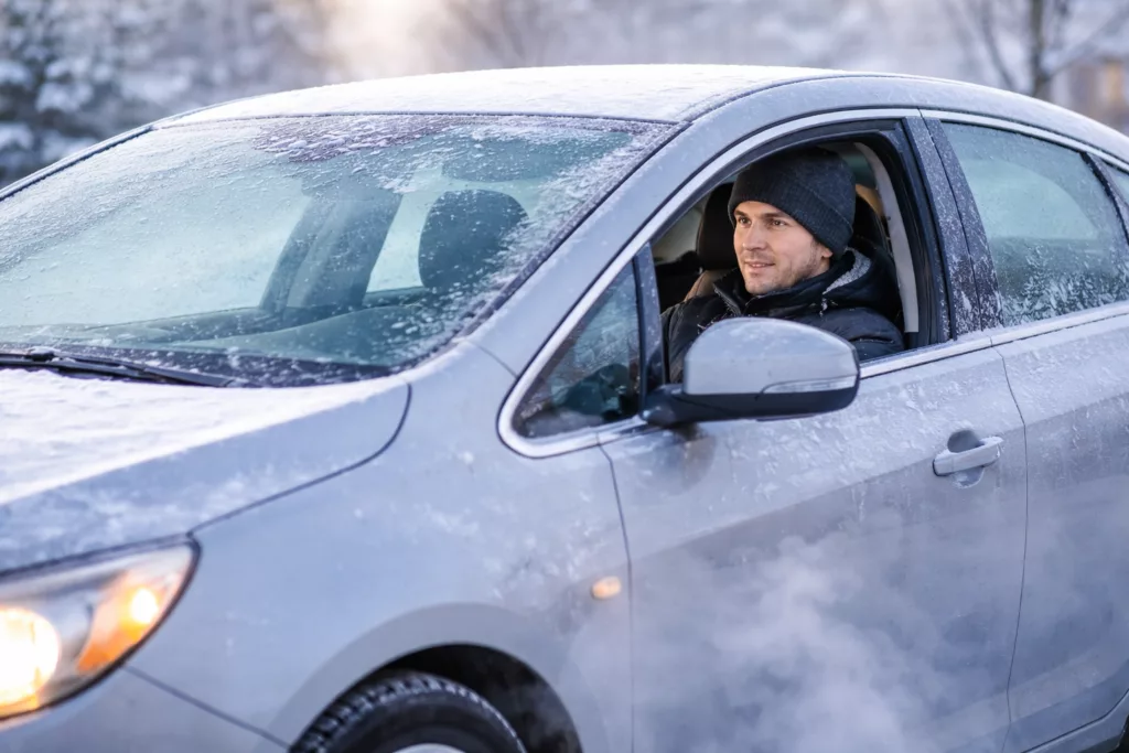 man sitting in his car warming it up