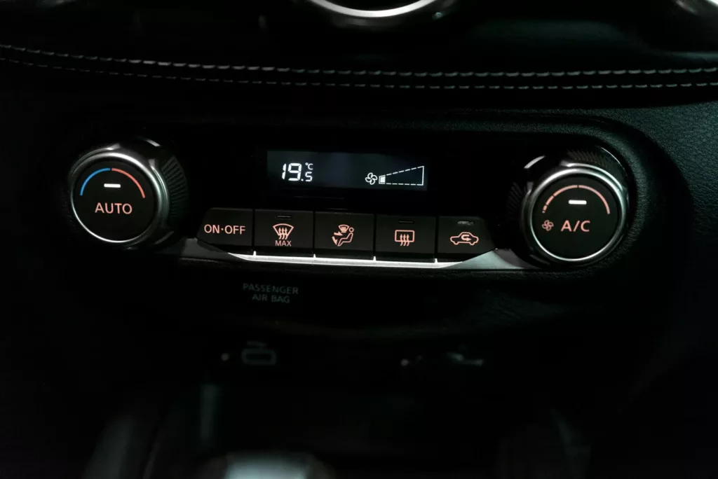Car automatic climate control panel with AUTO temperature dial on the left, A/C fan dial on the right, and the display reading 19.5°C — car AC repair and recharge service at Rite-Price Auto Service Centre in Calgary, AB