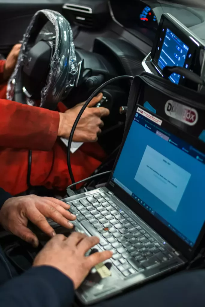 Diagnostic technician running a laptop scan tool to read vehicle codes at Rite-Price Auto Service Centre in Calgary, AB